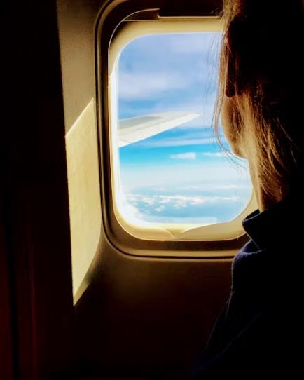 A woman looking out of an airplane window.