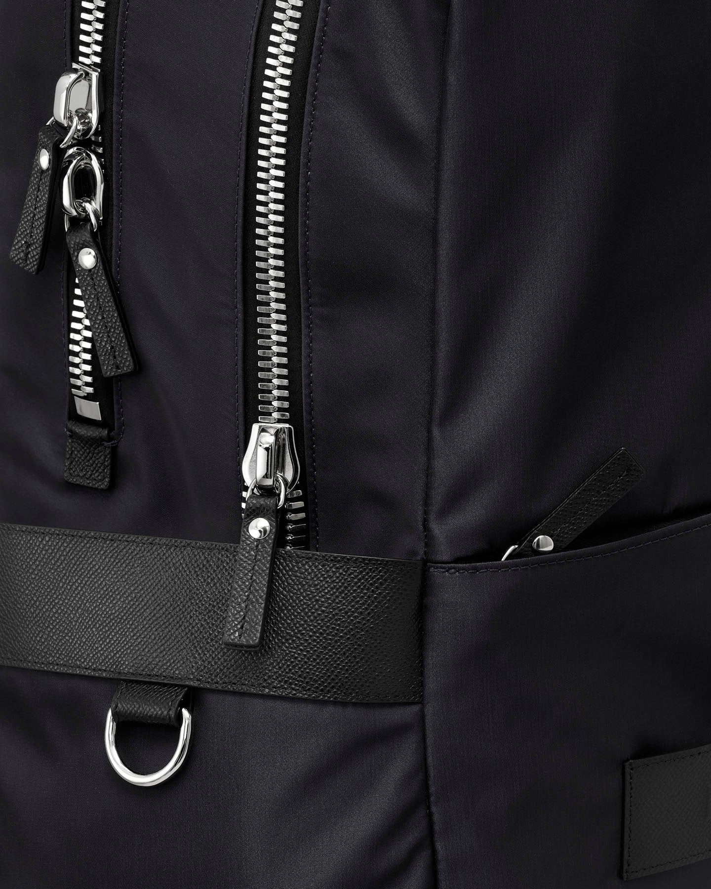 Close-up of a black backpack with zippers and a strap.