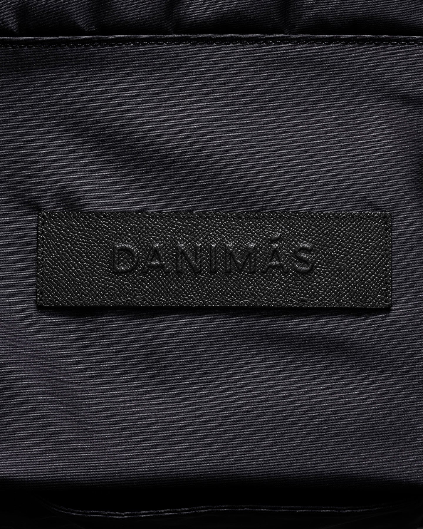 Black backpack with 'DANIMAS' branding on a black background
