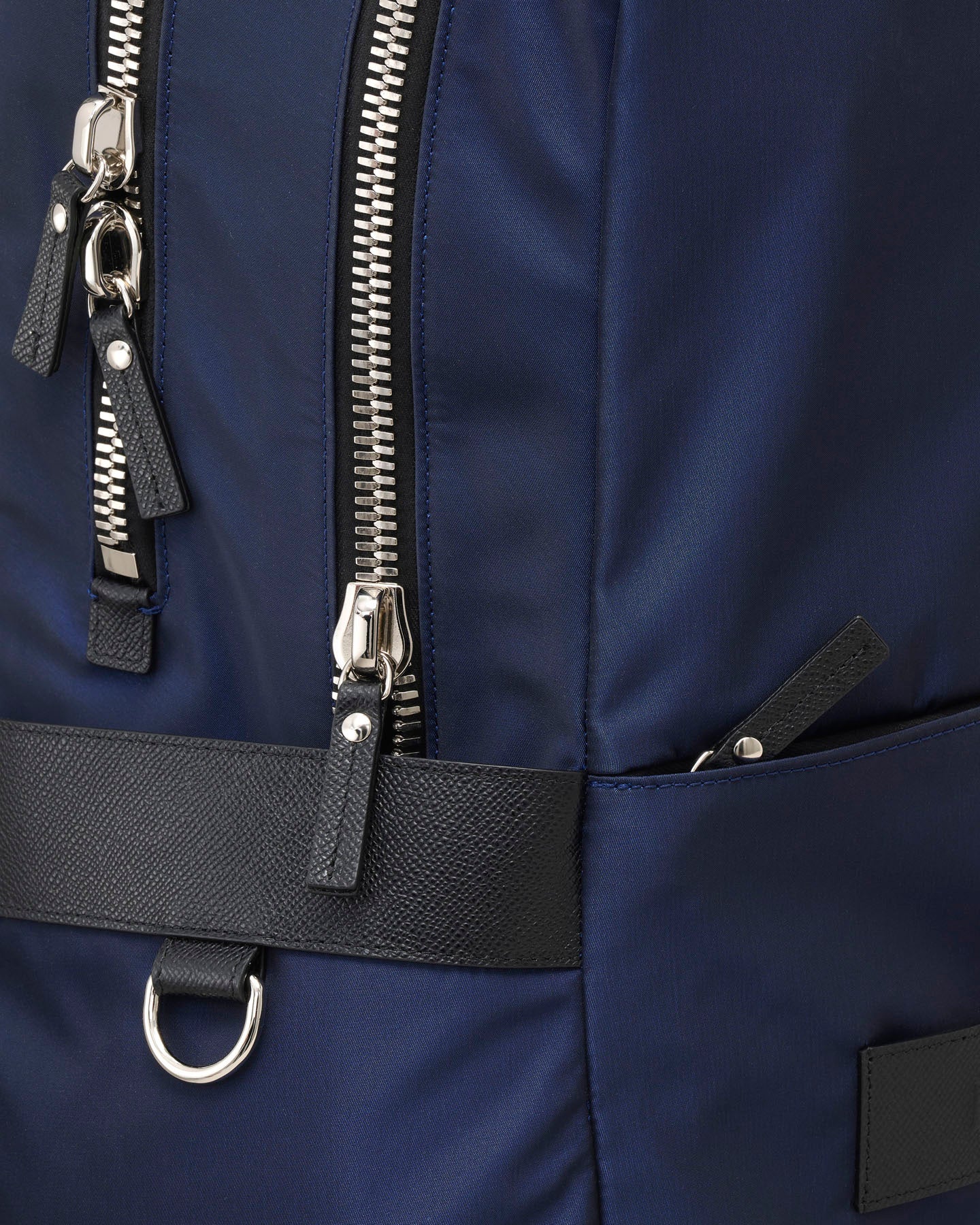 Close-up of a navy blue backpack with zippers and a black strap.