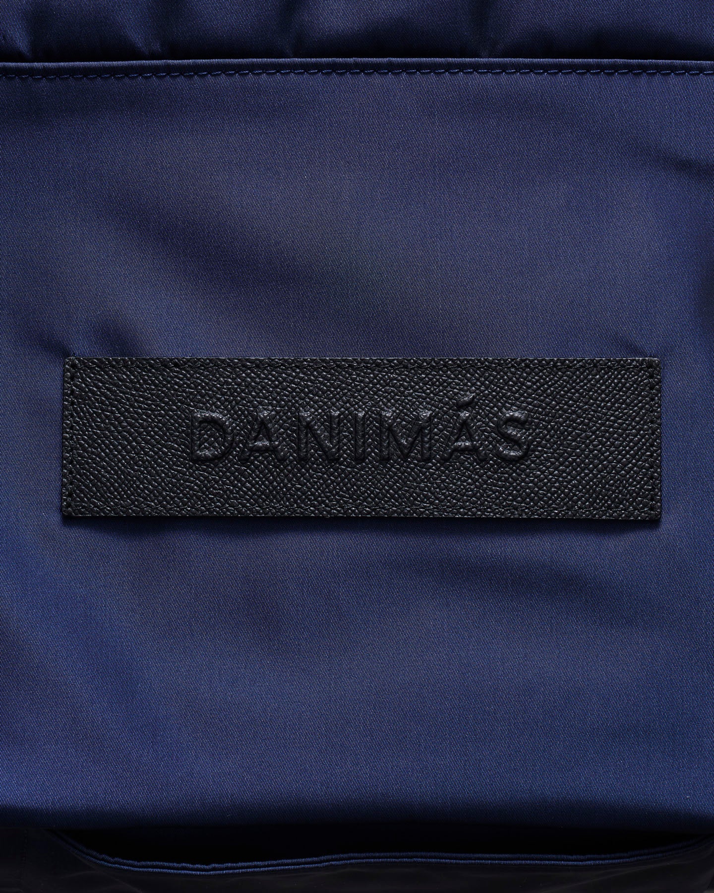 Navy blue bag with a black brand logo on a dark background
