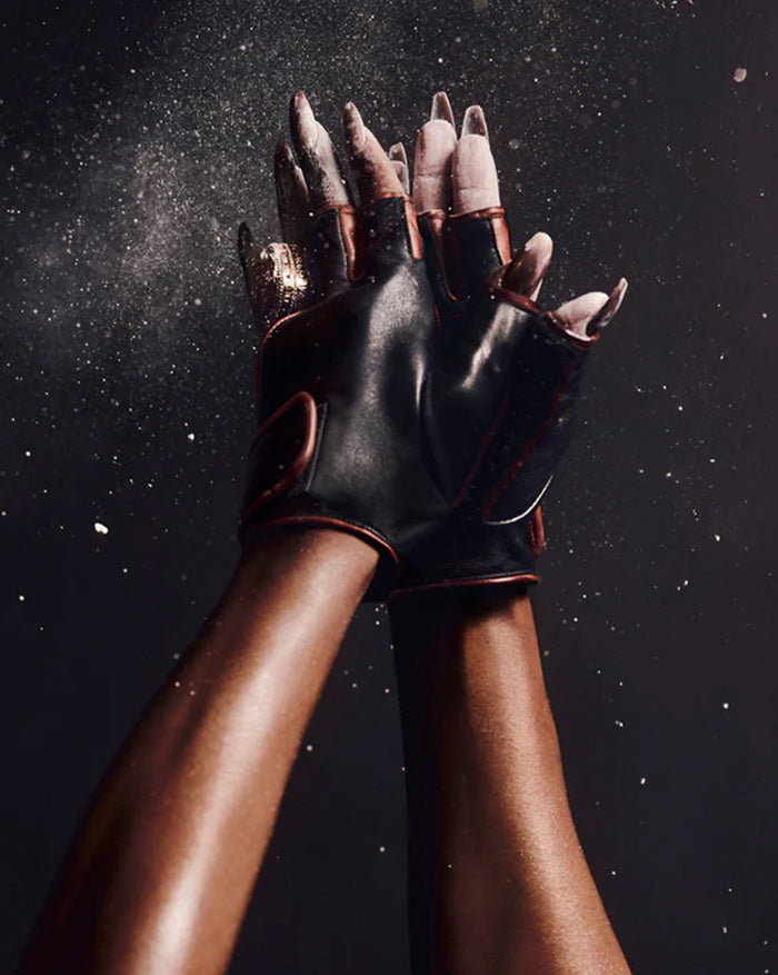 Black leather gloves held against a dark background