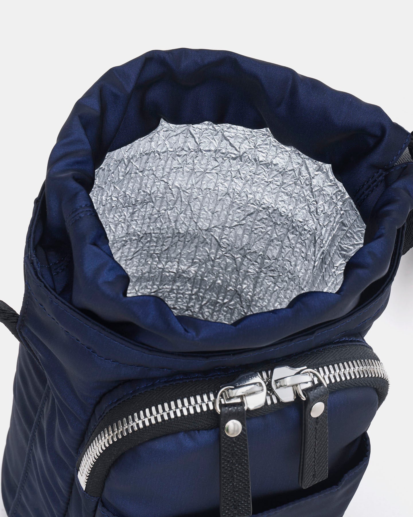 Navy blue crossbody water bottle bag with a silver interior lining on a white background