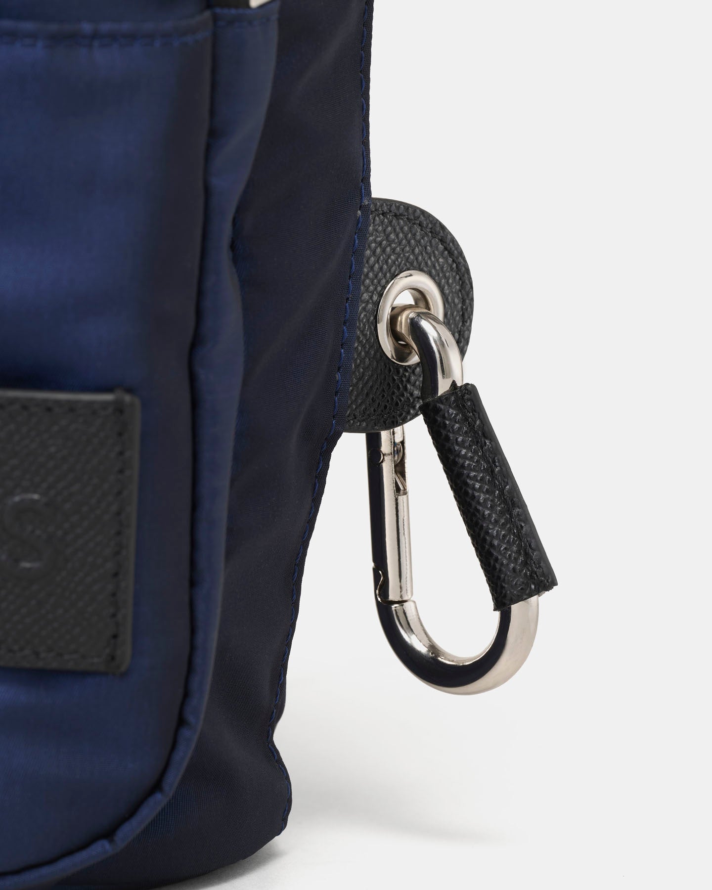Close-up of a blue crossbody water bottle bag with a carabiner on a white background