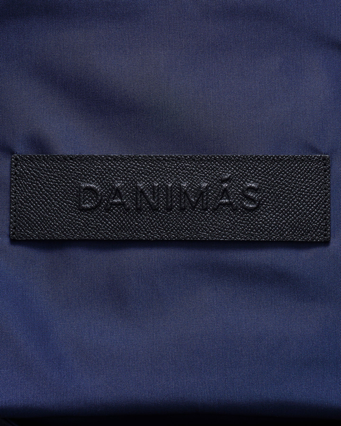 Black 'DANIMAS' logo on a blue fabric background